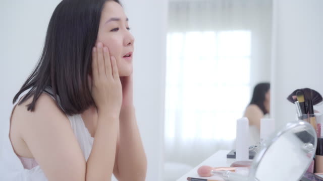 Beauty-blogger-present-beauty-cosmetics-sitting-in-front-camera-for-recording-video.-Happy-beautiful-young-Asian-woman-use-cosmetics-review-make-up-tutorial-broadcast-live-video-to-social-network.