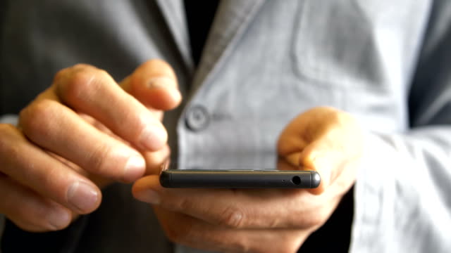 Männerhände-in-einer-Jacke-arbeiten-mit-einem-Touchscreen-Smartphone.