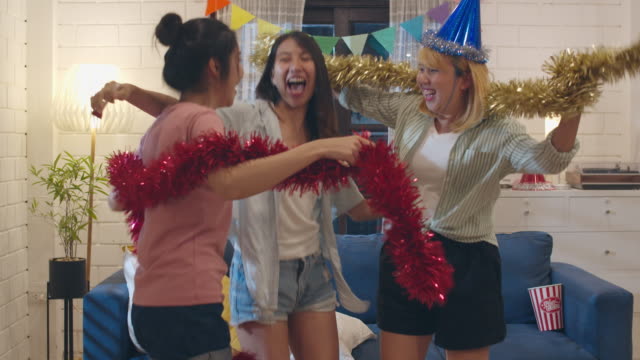 Group-of-Asian-women-party-at-home,-female-dancing-singing-and-listening-music-having-funny-together-in-living-room-in-night.-Teenager-young-friend-play-game,-celebrate-holiday-concept.-Slow-motion.
