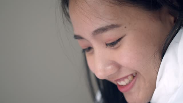 Cerrar-retrato-mujer-asiática-sonriendo-y-usando-una-tableta-en-el-dormitorio-navegando-en-las-redes-sociales-en-línea-compartiendo-estilo-de-vida.