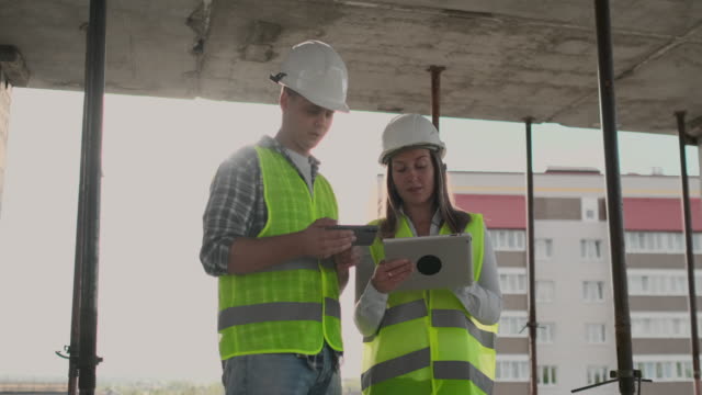 Supervisor-of-a-building-under-construction-man-discussing-with-engineer-designer-woman-the-progress-of-construction-and-examines-a-building-plan