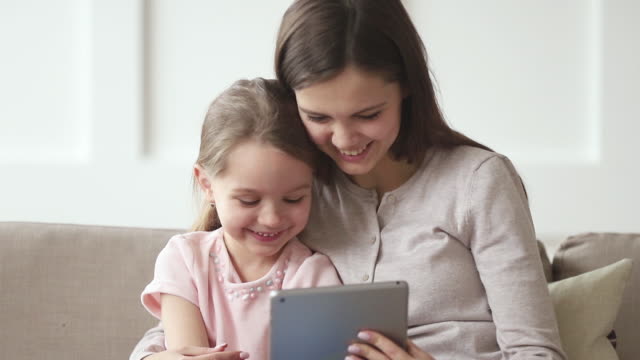 Glückliche-Mutter-und-Kind-Tochter-beobachten-lustige-Cartoons-auf-Tablet