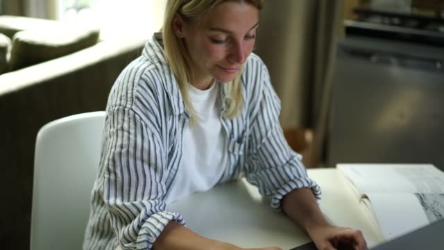 Caucasian-female-blogger-typing-text-of-publication-for-social-networks-on-laptop-computer-sitting-at-table-at-home-interior-and-working-on-freelance