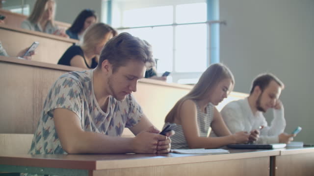Multi-Ethnische-Gruppe-von-Studenten-mit-Smartphones-während-der-Vorlesung.-Junge-Menschen,-die-soziale-Medien-während-des-Studiums-an-der-Universität-nutzen.