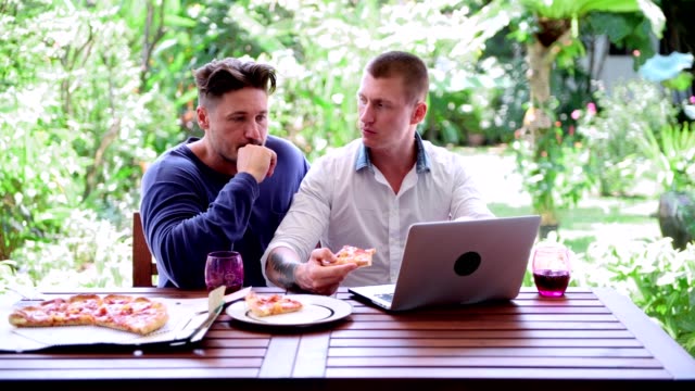 Gay-couple-having-pizza-for-lunch.-Disagree-on-something.