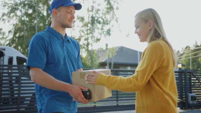 Beautiful-Young-Woman-Opens-Doors-of-Her-House-and-Meets-Delivery-Man-who-Gives-Her-Cardboard-Box-Package,-She-Signs-Electronic-Signature-POD-Device.