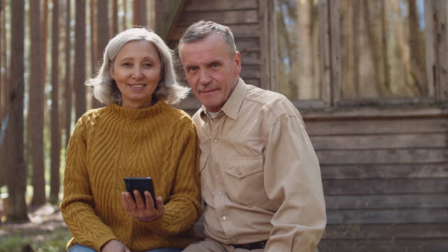 Portrait-of-Aged-Couple-near-Wooden-Country-House