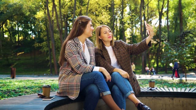 Hermosos-bloggers-streaming-en-vivo-usando-teléfono-inteligente-en-el-parque-público