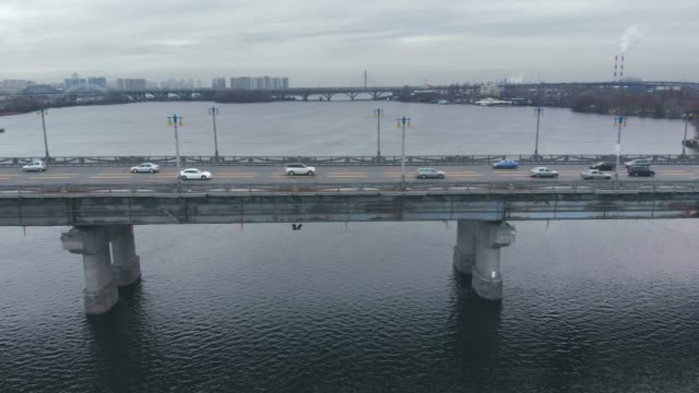 Verkehr-auf-einer-Brücke-über-einen-breiten-Fluss-im-Winter