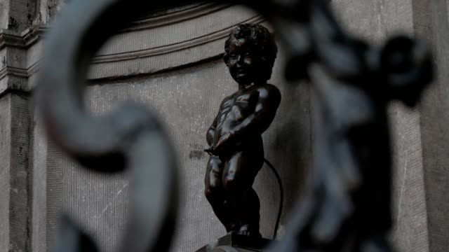 Manneken-Pis,-una-pequeña-escultura-de-bronce,-en-Bruselas-en-primavera-visto-a-través-de-una-valla