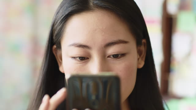 Handheld-view-of-Vietnamese-woman-looking-at-smart-phone