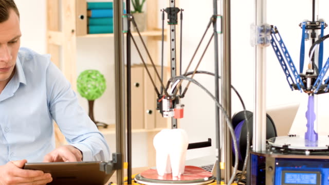 Concentrated-man-working-with-3d-printer