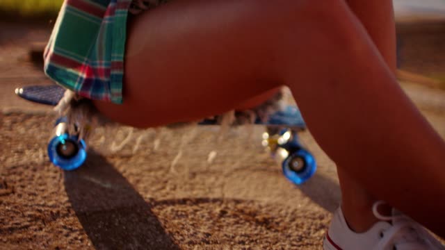 Schöne-junge-Mädchen-sitzen-auf-Skateboard-und-SMS