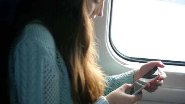 Junges-Mädchen-Reisen-in-einem-Zug-und-Mobiltelefon-zu-benutzen.-Schöne-Frau-sendet-eine-Nachricht-vom-Smartphone.-Attraktives-Mädchen-mit-Freunden-chatten.