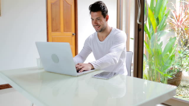Hombre-joven-de-trabajo-con-mesa-de-ordenador-portátil-ordenador-sentada-en-casa-chico-sonriente-escribiendo