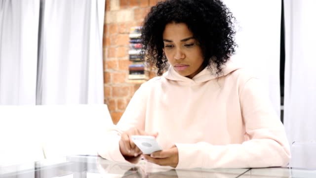 Mujer-afroamericana-en-el-trabajo-navegando-en-Smartphone-en-oficina