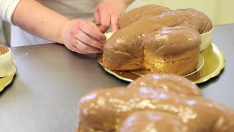 pastry-chef-hands-garnish-Easter-sweet-bread-cakes-with-fondants-sugar-paste,-closeup-on-the-worktop-in-confectionery