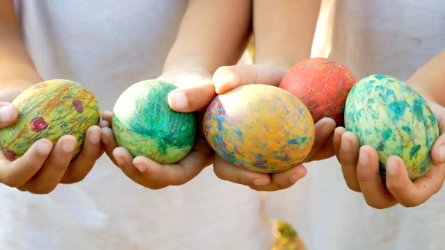 Close-up-of-two-children-hand-holding-a-easter-eggs-in-sunshine-background