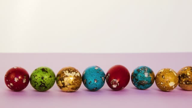 Hermosas-varios-colores-los-huevos-de-Pascua-alineados-en-una-fila-en-una-superficie-de-color-de-rosa.