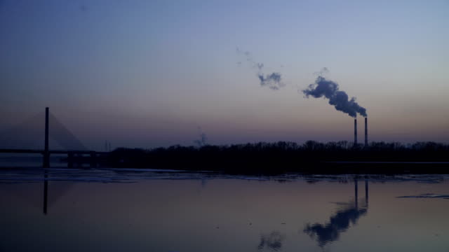 The-smoky-plant-on-the-background-of-the-river-and-the-setting-sun