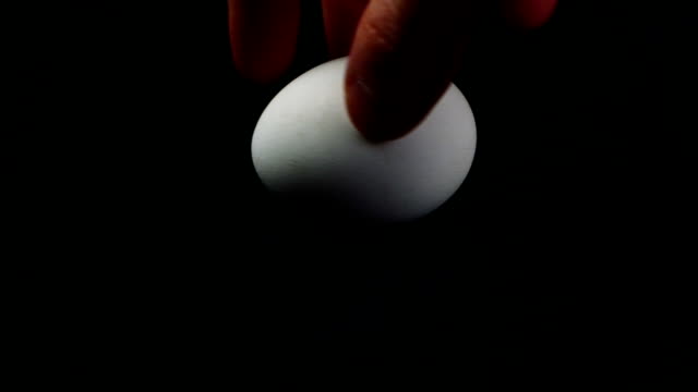 hand-of-a-man-turns-a-chicken-egg-on-a-table