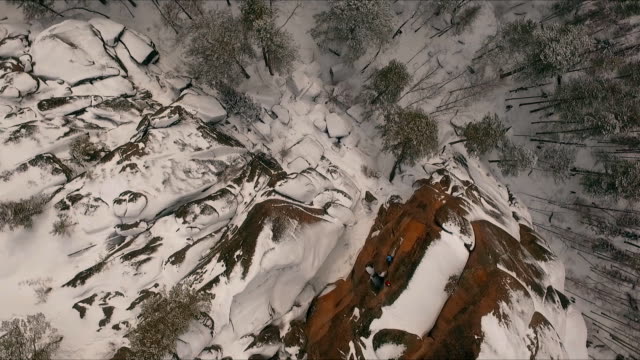 Vista-aérea-de-un-escalador-subiendo-un-acantilados-durante-un-día-de-invierno-soleado.