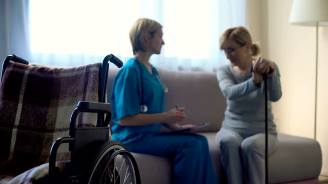 Enfermera-y-edad-mujer-sentada-en-sofá-del-hospital,-discutir-noticias,-apoyo