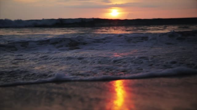 Close-Up-Of-Waves-Rolling-Up-The-Sandy-Beach-at-sunset