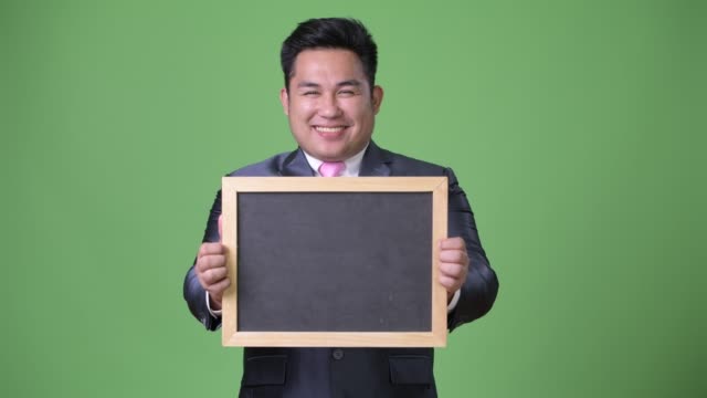 Young-handsome-overweight-Asian-businessman-against-green-background