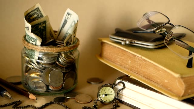 Books-with-glass-penny-jar-filled-with-coins-and-banknotes.-Tuition-or-education-financing-concept.-Scholarship-money.