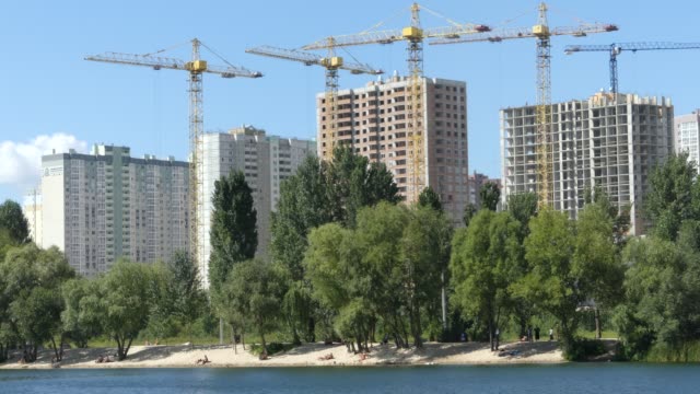 A-lake-against-the-background-of-houses-under-construction.-Skyscrapers-are-built-near-the-lake.-Construction-of-residential-buildings-near-the-lake.