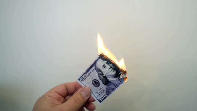 Hand-holding-a-burning-hundred-dollar-banknote