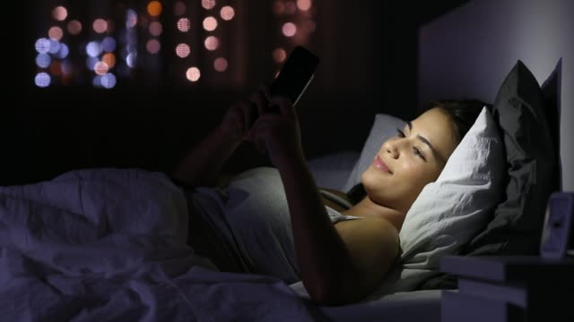 Happy-girl-chatting-in-a-phone-in-the-bed-in-the-night