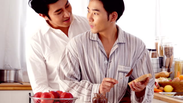 Dulce-feliz-pareja-gay-en-cocina-casera.-Hombre-que-cocina-el-desayuno-para-él-novio-con-sonrisa-atractiva.-Personas-con-gay,-homosexual,-concepto-de-relación.