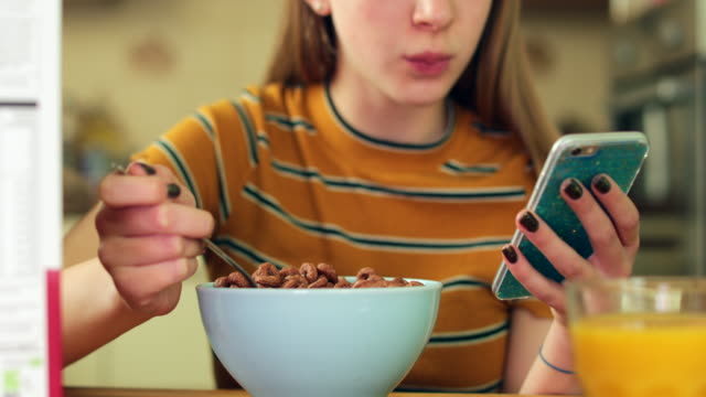 Teenager-Mädchen-essen-ungesund-Schale-mit-zuckerhaltigen-Frühstück-Getreide-SMS-auf-Handy