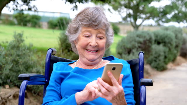 Ältere-Frau-mit-Handy-auf-Rollstuhl-4k