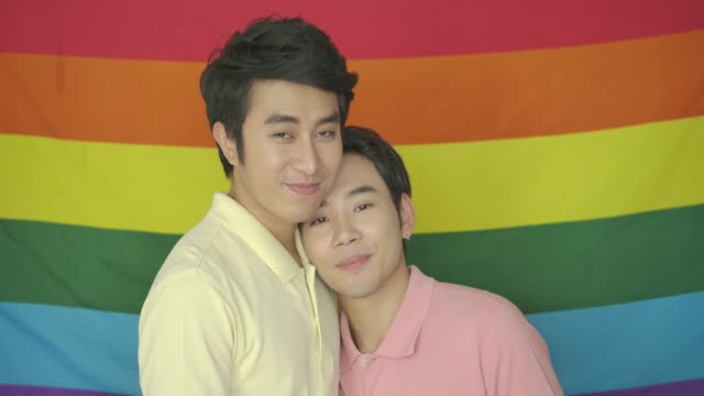 Porträt-des-jungen-asiatischen-schwules-Paar-posieren-vor-gay-Pride-Regenbogenfahne.