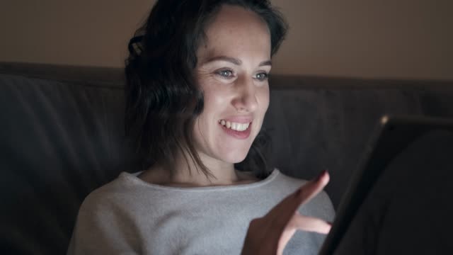 Mujer-sonriente-con-tableta-digital-en-la-noche
