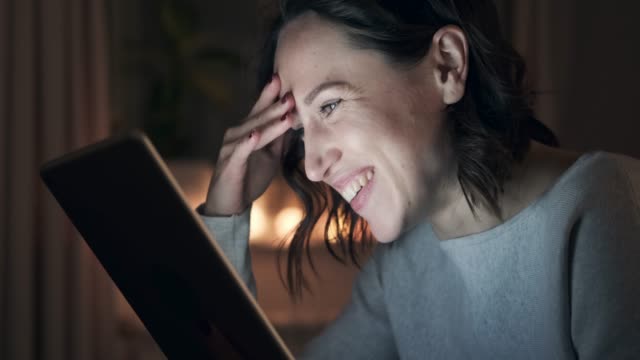 Cheerful-woman-using-digital-tablet-at-night