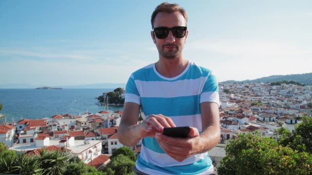 Man-using-cellphone-on-the-ocean-/-sea-small-town-coast.