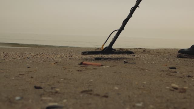 Mann-am-Meer-mit-einem-Metalldetektor-sucht-Schatz-im-Sand
