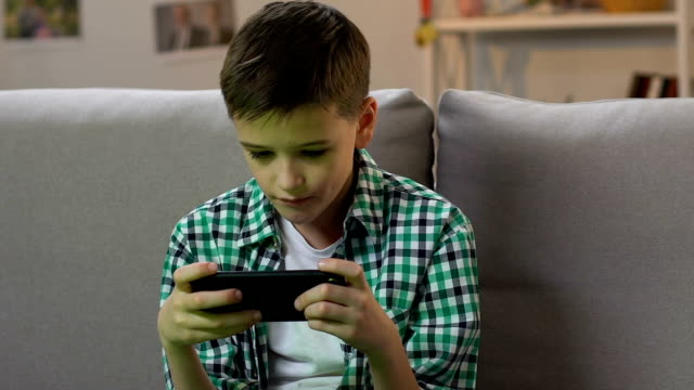 Boy-jugando-videojuego-en-el-teléfono-inteligente-en-casa,-adicción-gadget-en-la-edad-temprana
