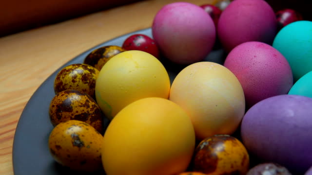 Woman's-hand-puts-red-and-green-colored-quail-egg