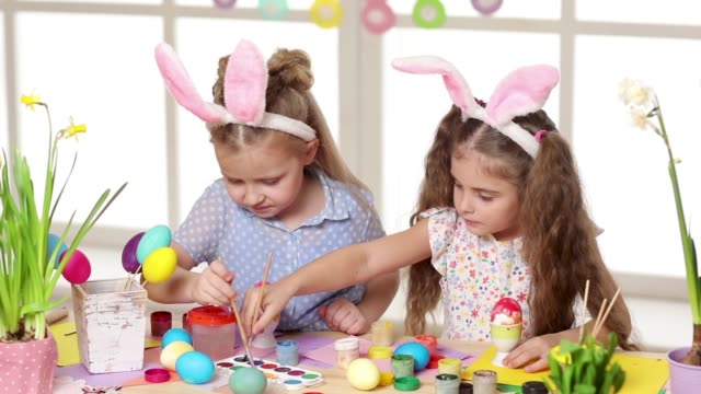 Glückliche-Kinder,-die-am-Ostersamstag-hanzige-Ohren-tragen-und-Eier-malen.