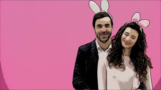 Young-creative-couple-on-pink-background.-With-hackneyed-ears-on-the-head.-During-this,-two-show-the-gestures-of-the-class-and-look-at-one-another-together.-Easter-concept.