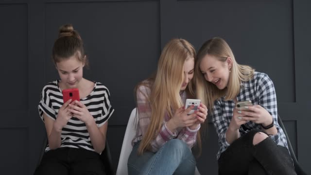 Chicas-adolescentes-divirtiéndose-mientras-que-los-mensajes-de-texto-en-los-teléfonos-móviles