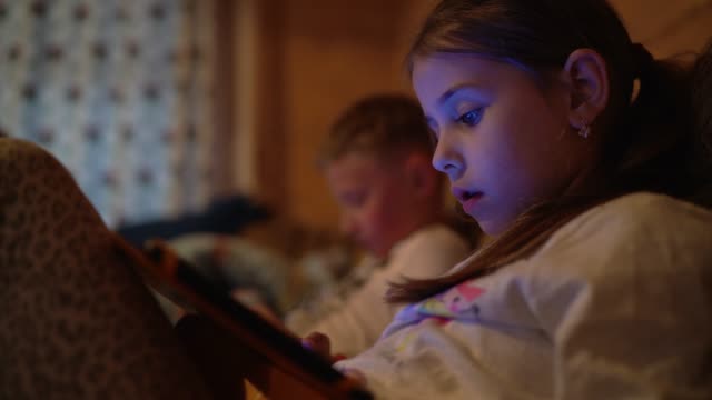 4K-dos-niños-que-juegan-en-sus-dispositivos-portátiles