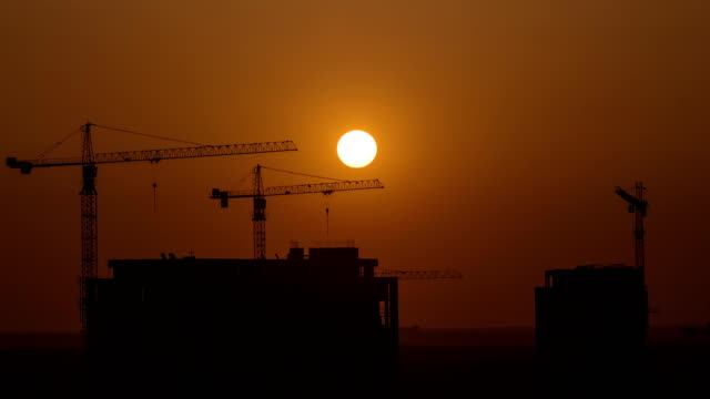 Das-Gebäude-mit-Kränen-auf-Sonnenuntergang-hintergrund.-Zeitraffer