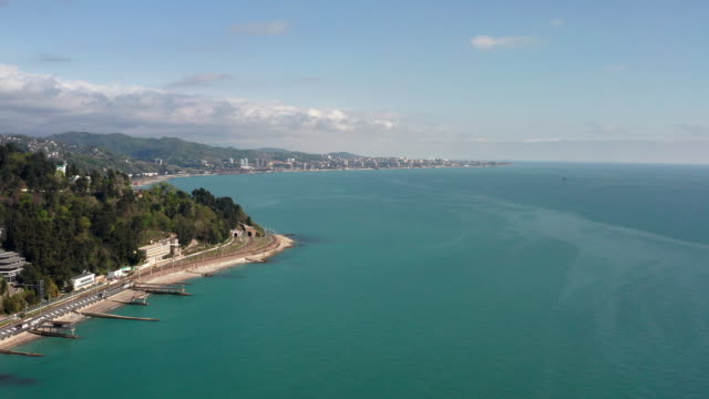 Aerial-video-shooting.-The-black-sea-coast-of-Sochi.-City-resort.-Hotels-by-the-sea.-Holiday-season.-Railway-along-the-coast.-Panoramic-view-of-Adler.-Clear-blue-sky.