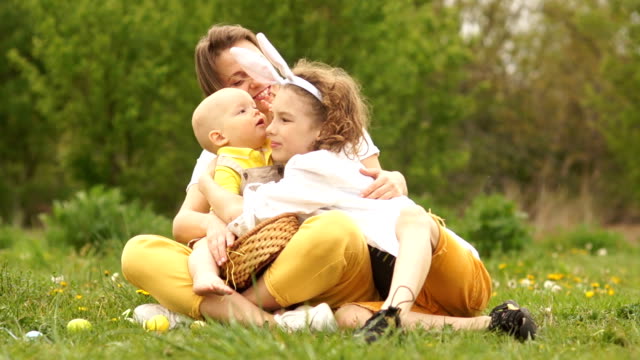 Encantadora-familia-abrazando-en-el-parque-en-un-picnic.-Feliz-familia-de-Pascua.-Mamá-y-dos-hijos.-Día-de-las-madres